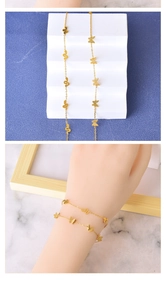 Detail of layered gold bracelet featuring butterfly and snake charms on a white stand
