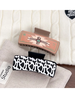 Detail of western style hair claws with cow print and ethnic pattern on fabric background
