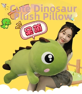 Close-up of a large green dinosaur plush pillow held by a model to show its soft size