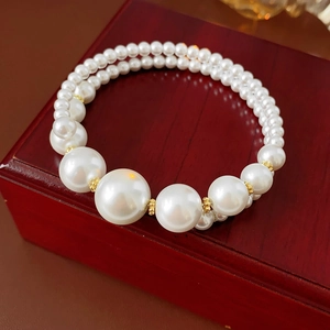 Détail d'un bracelet vintage en perles à deux rangs avec perles dorées sur écrin bijoux