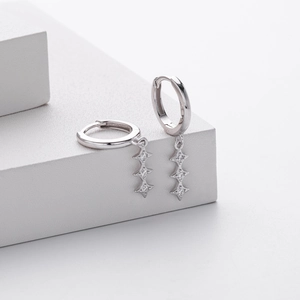 Détail macro de boucles d'oreilles créoles en argent 925 avec trois breloques étoiles
