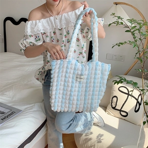 Detail of blue and white striped tote bag showing bubble textured fabric and logo patch