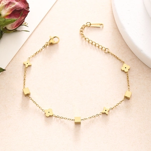 Detailed macro view of a gold-plated double-layer bracelet with floral geometric pendants