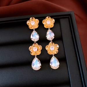 Détail macro de boucles d'oreilles fleurs plaquées or 18 carats avec pampilles cristal