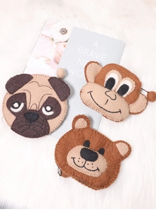 Detailed view of handmade felt animal coin purses featuring pug, monkey and bear designs