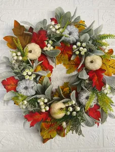 Close-up of autumn wreath with maple leaves, white berries and glitter pumpkins