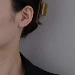 Minimalist 925 sterling silver ball stud earrings shown on model with light grey background