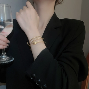 Detailed view of a gold snake-shaped multi-layered bracelet with textured scales