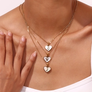 Drielaagse gouden ketting met hartvormige letterhangers en schelpafwerking voor dames