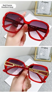 Detail of red oversized sunglasses with gradient lenses and golden metal temples