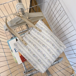 Floral canvas tote bag with purple flower patterns in a metal shopping basket detail
