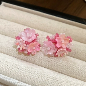 Macro shot of pink fabric flower earrings with beaded stamens on jewelry box lining