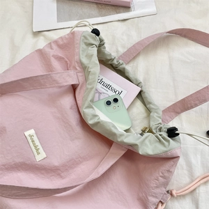 Detail of pink nylon drawstring tote bag interior showing large capacity for books and phone