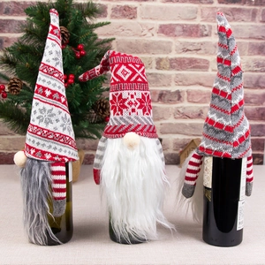 Three Christmas gnome wine bottle covers with knitted snowflake patterns and faux fur