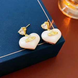 Detailed view of heart-shaped earrings with gold plating and white mother of pearl finish