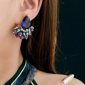 Detail of bohemian drop earring with blue crystal and purple beads on model's ear