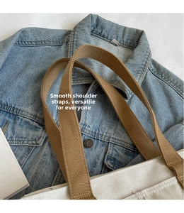 Detail of canvas tote bag with brown woven shoulder straps and beige fabric texture