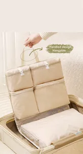 Dettaglio dell'organizzatore da viaggio beige con scomparti a zip e fibbie nella valigia
