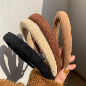 Four slim faux suede headbands in black, beige, dark brown, and khaki on a hand