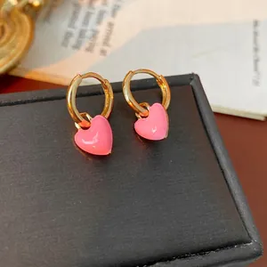 Vintage style gold hoop earrings with pink enamel heart pendants on black jewelry box