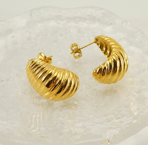 Detailed close-up of gold croissant dome hoop earrings with textured spiral ridges