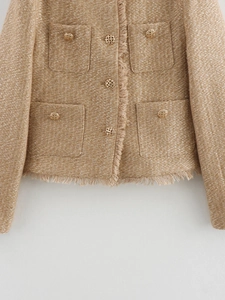 Close-up of champagne tweed jacket featuring metallic gold hollow buttons and fringe trim