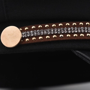 Makroansicht einer schwarzen Schirmmütze mit Goldnieten und Kristallen auf dem Samtband