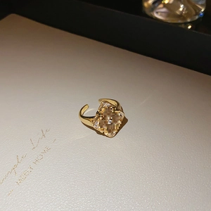 Close-up of a gold-plated flower ring with a large square centerpiece and tiny inset gems