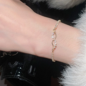 Detailed close-up of a gold zircon-inlaid infinity bracelet worn on a female wrist