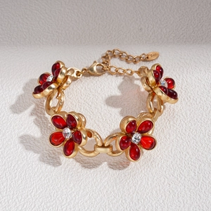 Detailed view of gold chain necklace with red glass flower charms and lobster clasp closure