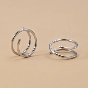 Close-up of silver stainless steel double spiral nose rings with metal beads