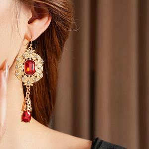 Detailed close-up of vintage gold drop earrings featuring red ruby-colored gemstones