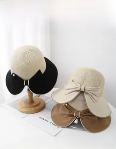 Dettaglio di cappelli di paglia a tesa larga con fiocchi eleganti e loghi metallici