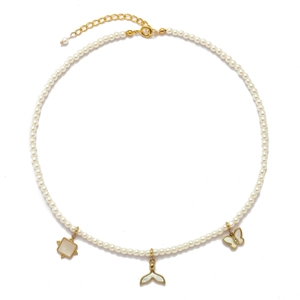 Macro detail of gold butterfly and fishtail pendants on a white pearl necklace