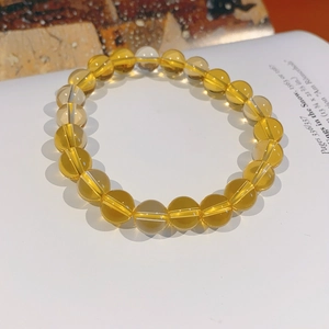 Detailed view of yellow citrine beaded bracelet displayed on a white open book