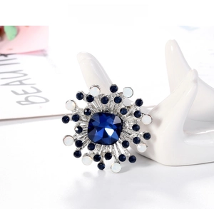 Detail of a vintage geometric brooch with a large blue crystal and sunburst setting