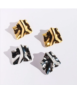 Macro shot of mirror-polished gold and silver irregular geometric pleated earrings