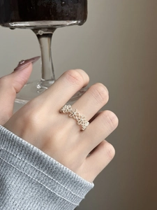 Detail shot of a silver hollow flower ring with matte texture on a woman's hand