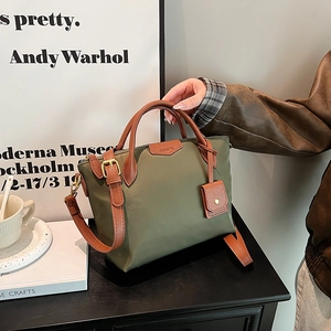 Olive green nylon tote bag with brown leather handles and adjustable shoulder strap