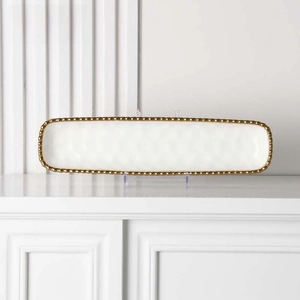 Close-up of a white rectangular ceramic plate with gold beaded edges and hammered texture