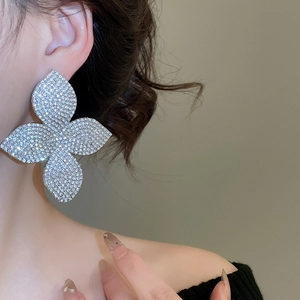 Dettaglio macro di grandi orecchini a fiore d'argento con strass scintillanti sulla modella