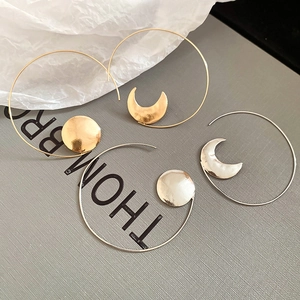 Detail of asymmetric geometric moon earrings in gold and silver plated metal finishes