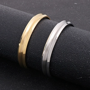 Dettaglio dei bracciali a C in oro e argento su un espositore cilindrico nero opaco