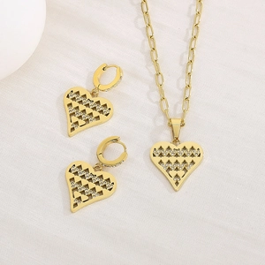 Elegant gold jewelry set with hollow heart pendants and crystal accents on white fabric