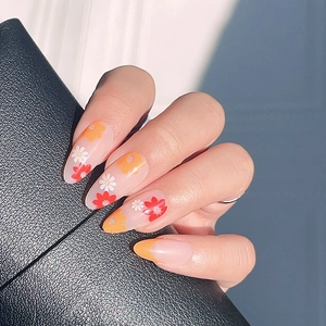 French press-on nails with red and yellow daisy floral design on oval nude base