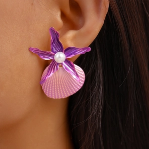 Close-up of beach style purple starfish and pink shell earrings worn by a model