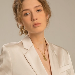 Detail of gold-plated geometric pendant necklace and hoop earrings on model