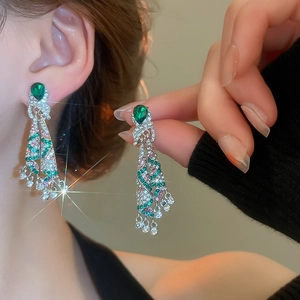 Macro shot of silver needle drop tassel earrings with green crystals and rhinestones