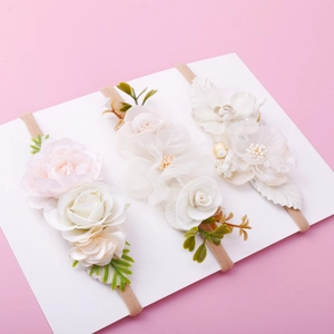 Detailed close-up of three floral baby headbands with pink roses on a soft stretch nylon band