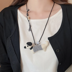 Detail of dog pendant with black and white checkered coat on a black woven adjustable cord